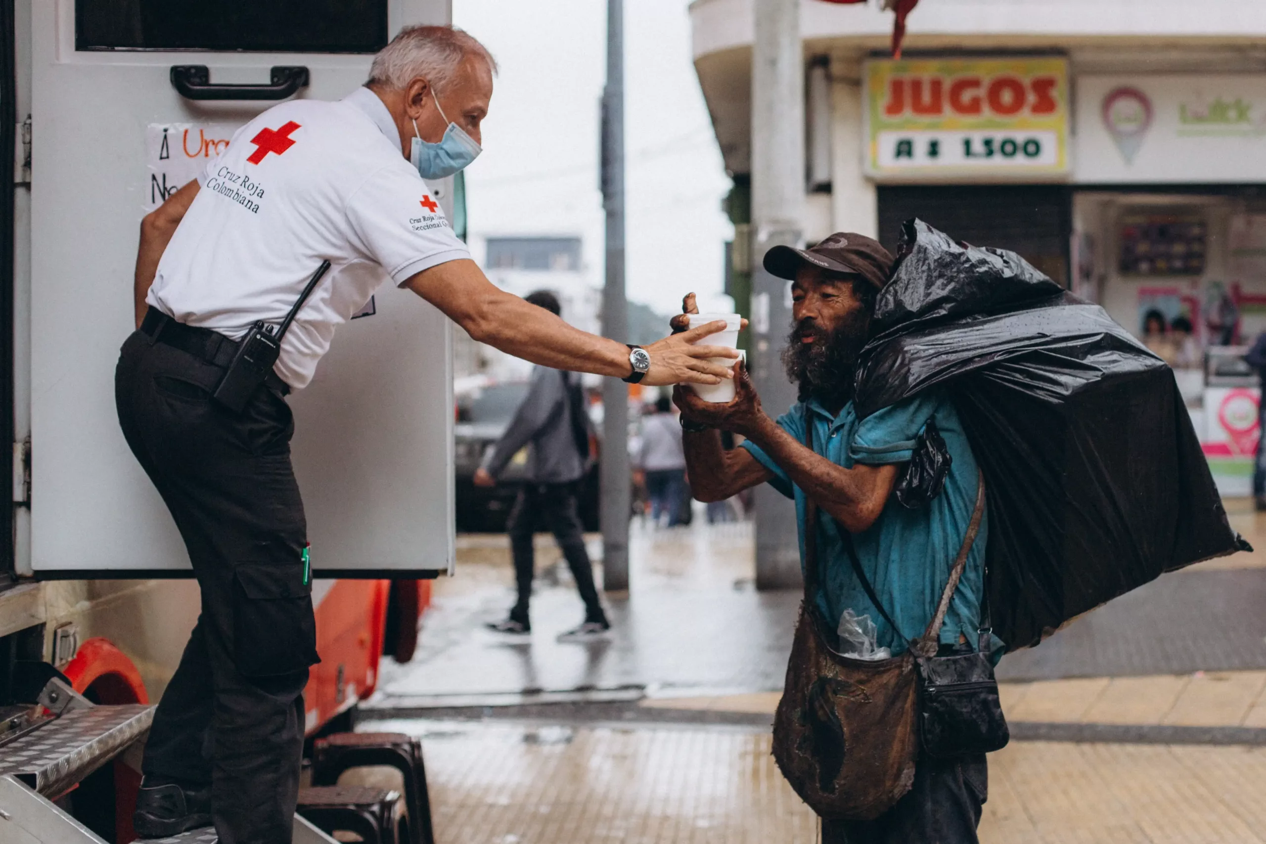 medic handing homeless man coffee